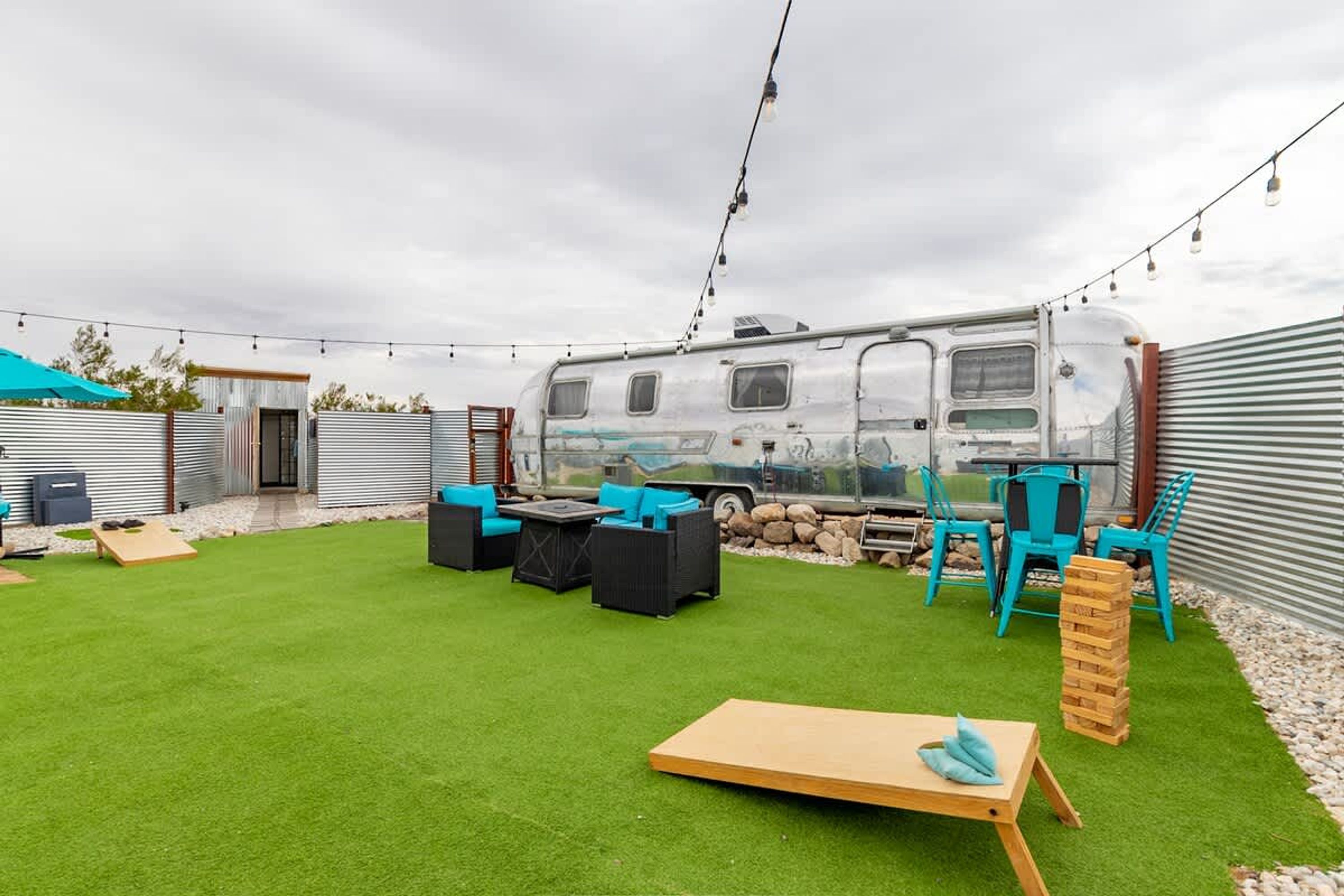 A recreational area with artificial grass, outdoor furniture, and a camper van.