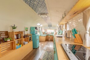 A compact, well-lit room with a kitchenette, a seating area, and a small table.