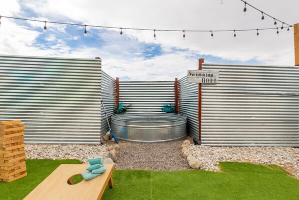 A swimming hole with a wooden bench and a sign indicating its name.