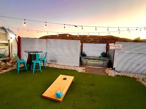 Un patio exterior con mesa de billar, sillas y un letrero que indica una piscina natural.