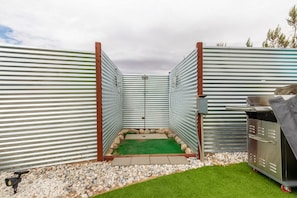 A fenced outdoor area with a grill and a small artificial turf play area.