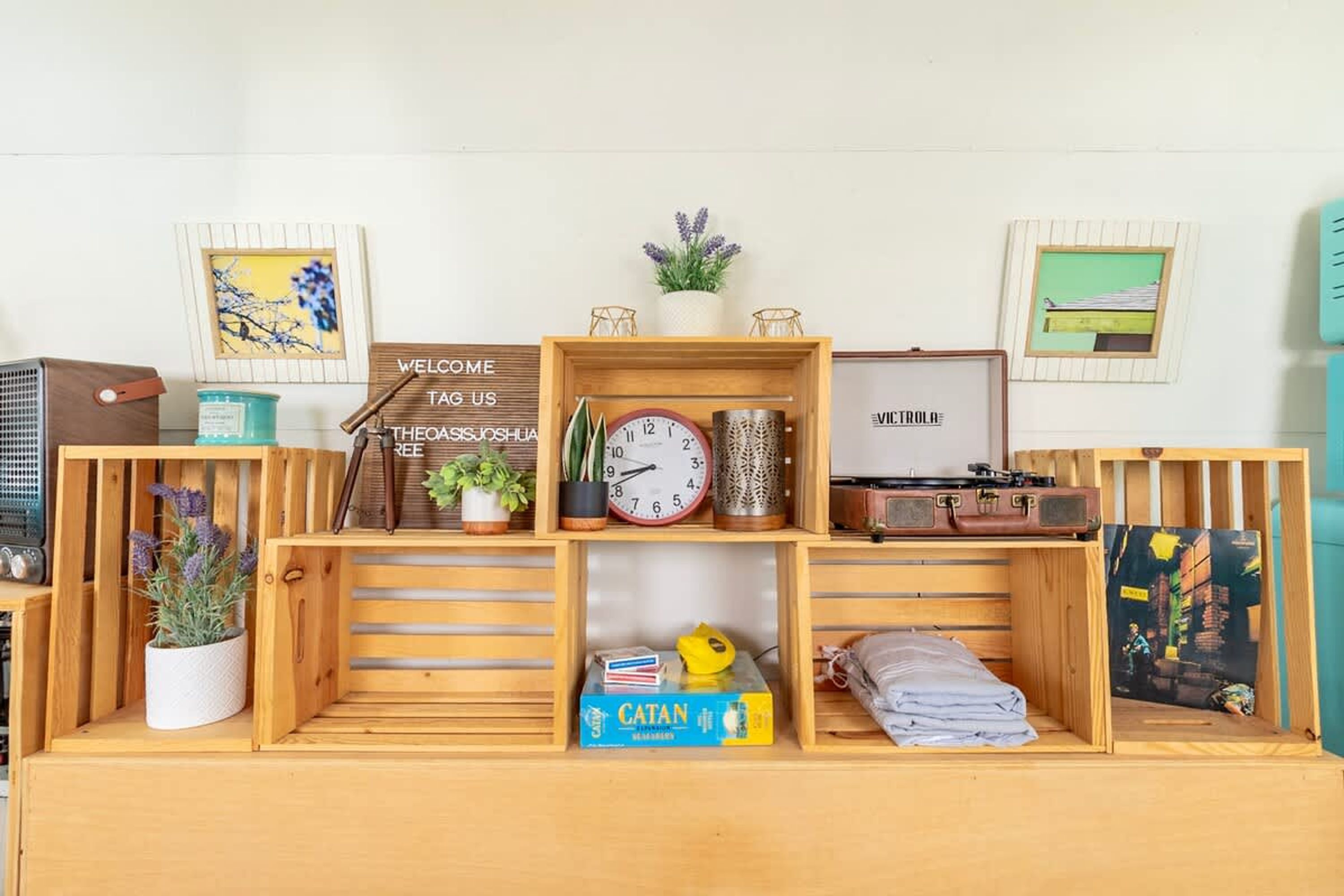 A wooden shelf unit with various items including a clock, a plant, and a framed picture.