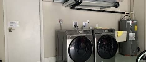 A laundry room with two front-loading washing machines, a water heater, and a door with a doormat.