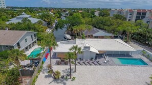 A residential area with a swimming pool, a covered patio, and a view of the surrounding neighborhood. - Siesta Beach Getaway With Heated Pool (Siesta Key)