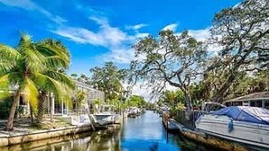 A canal with boats, palm trees, and a clear sky. - Siesta Beach Getaway With Heated Pool (Siesta Key)