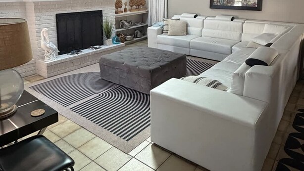 A modern living room with a white sofa, a fireplace, a flat-screen TV, and a ceiling fan. - Siesta Beach Getaway With Heated Pool (Siesta Key)