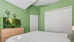 A bedroom with a bed, a dresser, a painting, and a closet. - Your Private Resort Tiki Bar Near Disney (Kissimmee)
