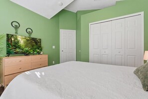 Ein Schlafzimmer mit einem Bett, einem Schminktisch, einem Gemälde und einem Kleiderschrank.