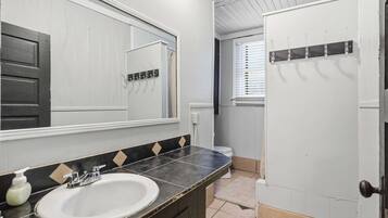 A bathroom with a white sink, a mirror, a towel rack, and a door.