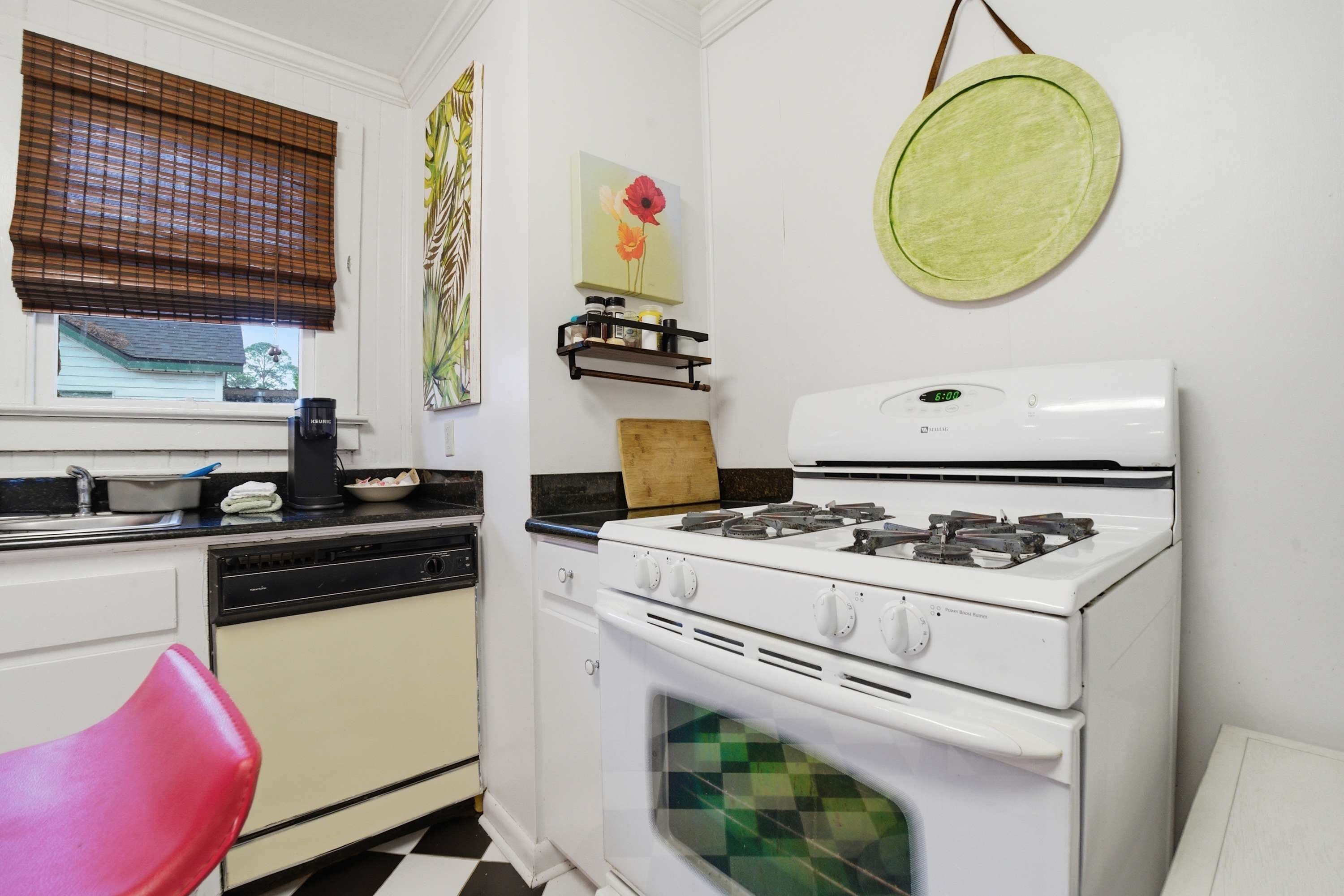 A kitchen with a stove, dishwasher, and a red chair.