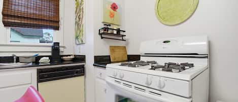 Une cuisine équipée d’une cuisinière, d’un lave-vaisselle et d’une chaise rouge.