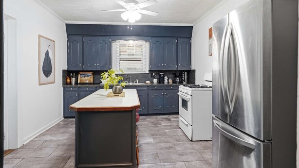 A kitchen with dark blue cabinets, a stainless steel refrigerator, a white stove, and a ceiling fan. - Private Bedroom in 4BR Home (Lafayette)