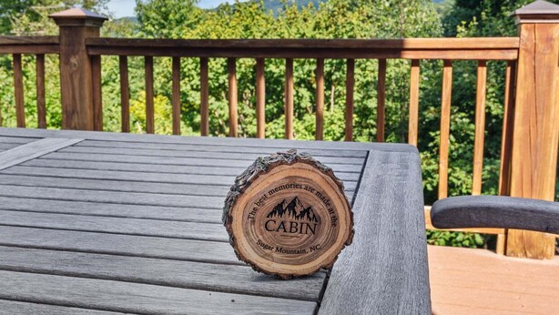 Eine Holzterrasse mit Metallgeländer, einem Holztisch und einem Untersetzer aus Holz mit Text.