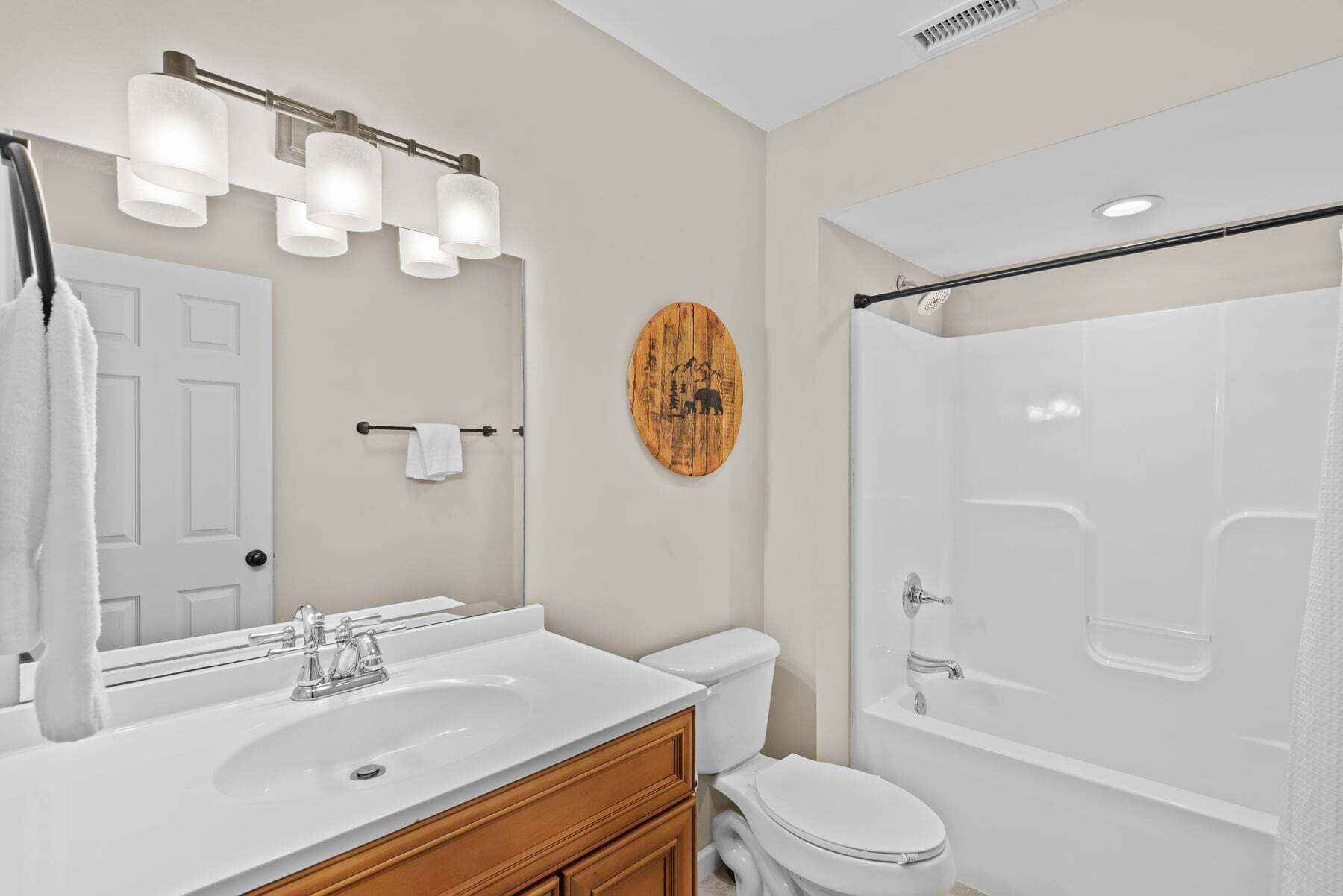 A bathroom with a white sink, a toilet, a bathtub, and a mirror with lights.