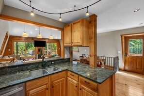 Eine Küche mit Holzschränken, Granit Arbeitsplatten und Pendelleuchten.