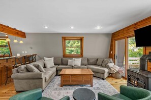 Una sala acogedora con un sofá modular, una mesa de centro de madera y una chimenea.