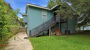 A two-story house with a front porch, a staircase leading to the upper floor, and a small front yard.