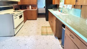 Eine kompakte Küche mit Holzausstattung, einer Mikrowelle, einem Kühlschrank und einem fußbodenbelag mit Muster.