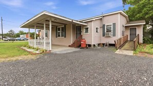 Ett enplanshus med en veranda framtill, en inglasad entré och en liten trädgård framför huset.