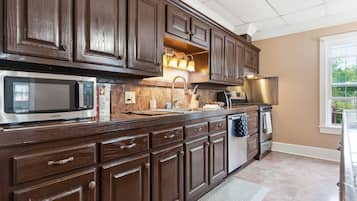 A kitchen with dark wooden cabinets, a stainless steel refrigerator, a microwave, and a sink.