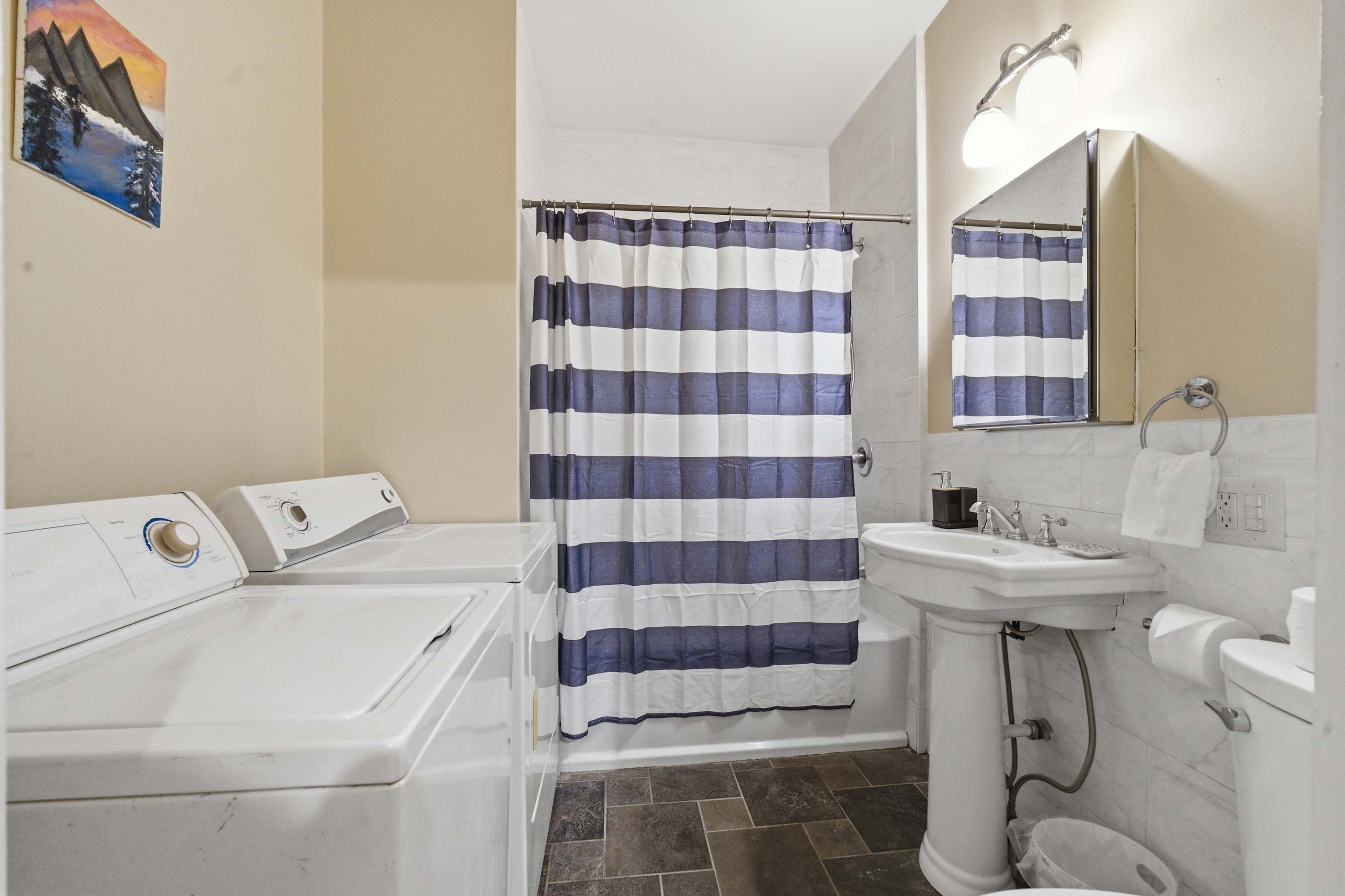 A bathroom with a striped shower curtain, a sink, a mirror, and a toilet.