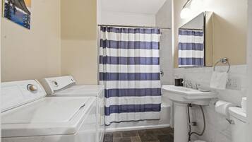 A bathroom with a striped shower curtain, a sink, a mirror, and a toilet.