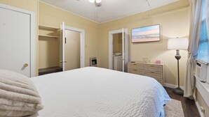 Ein Schlafzimmer mit einem Bett, einem Deckenventilator, einer Kommode, einer Lampe und einem Bild an der Wand.
