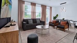 A modern living room with a sofa, coffee table, and dining area.