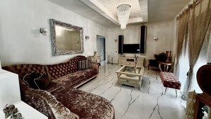 Ein Wohnzimmer mit einer Couch, einem Couchtisch, einem Fernseher und einer Deckenleuchte.