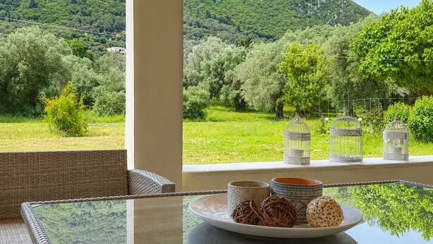 Ein Tisch mit Blick auf eine gebirgige Landschaft, Korbmöbel und Dekorationselemente.