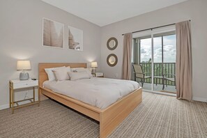 A hotel room with a bed, two bedside tables, a nightstand, a balcony with a view, and two wall-mounted mirrors.
