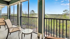 A balcony with a view of a natural landscape, a table, and two chairs. - Upstay Large Family Condo w Pool Sauna (Winter Garden)