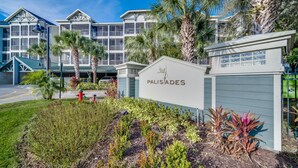 A hotel with a sign reading 'PALISTADES' surrounded by landscaped gardens and palm trees. - Upstay Large Family Condo w Pool Sauna (Winter Garden)