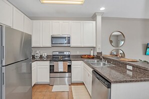 A modern kitchen with white cabinets, stainless steel appliances, a microwave, a stove, and a dishwasher. - Upstay Large Family Condo w Pool Sauna (Winter Garden)
