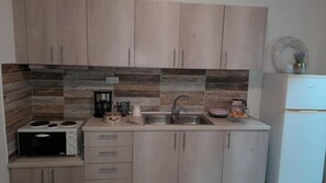 Eine Küche mit Holzschränken, einem Herd, einem Spülbecken und einem Kühlschrank.