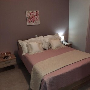 Ein Schlafzimmer mit einem Bett, Kissen, einem Nachttisch mit Lampe und einem Bild an der Wand.