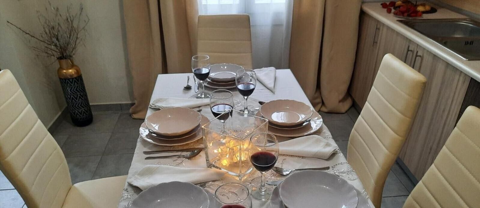 Een eettafel gedekt met borden, glazen en een kaars.