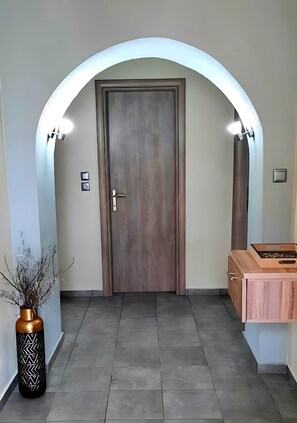 Ein Flur mit einer Holztür, einer Vase mit Zweigen und einem Holzschrank.