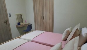 Ein Schlafzimmer mit zwei Betten, einem Schreibtisch, einem Stuhl und einem Kleiderschrank.