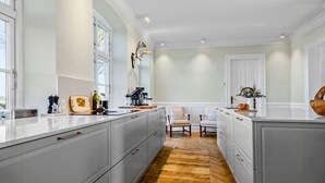 A spacious kitchen with a large island, white cabinetry, and a wooden floor. - Renovated farmhouse with views over Lillebælt (Sønder Stenderup)