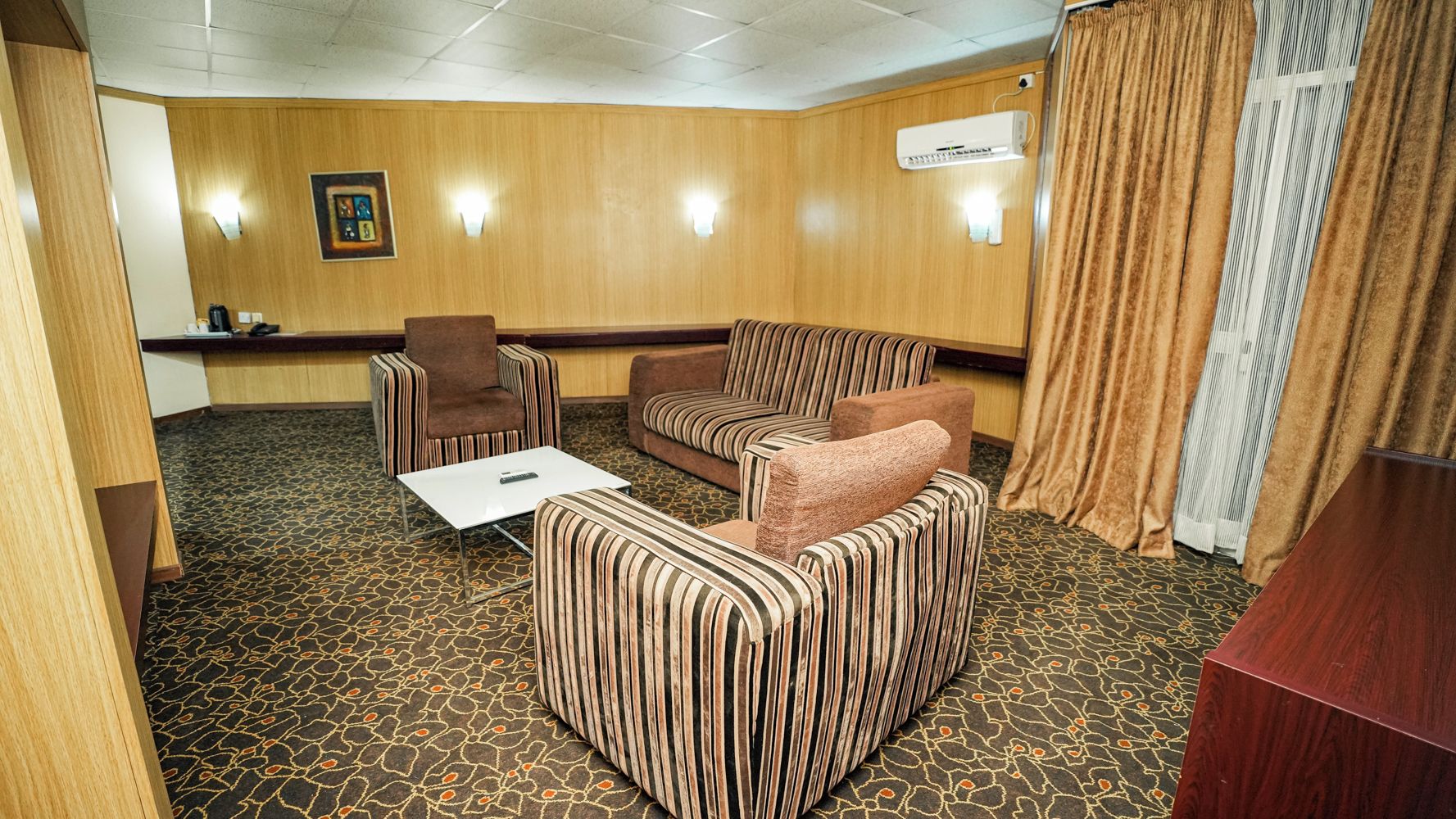Una habitación de hotel con sofá, sillón y una mesita.