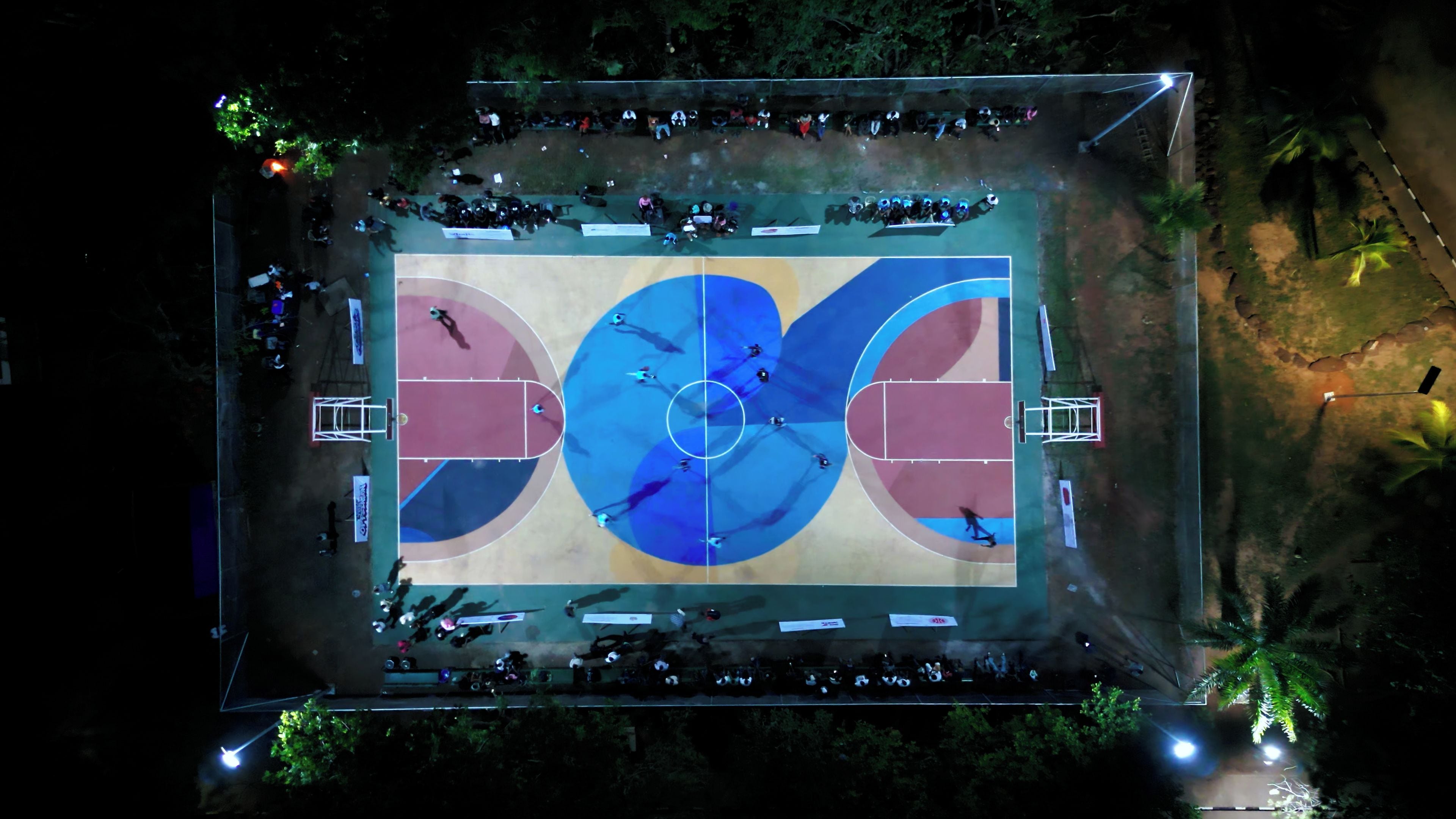 An outdoor basketball court surrounded by trees.
