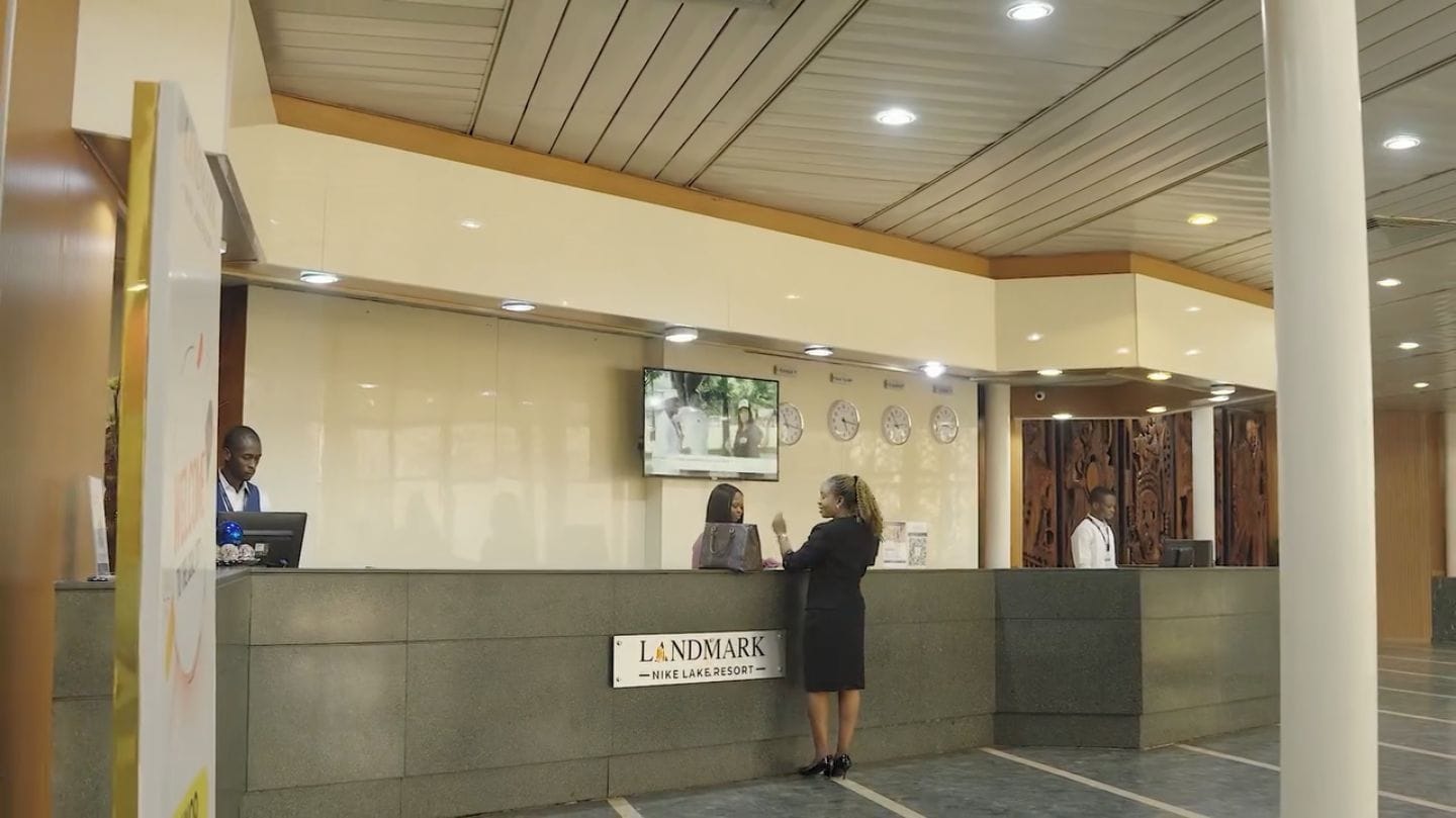 A reception desk at a hotel with a sign indicating it's the Landmark Nike Lake Resort.