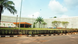 A modern building with a white facade and orange accents, surrounded by well-maintained greenery and a clear sky. - Landmark Nike Lake Resort (Enugu)