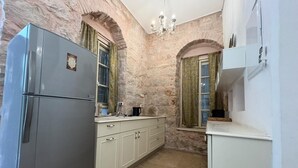 Una cucina con pareti in pietra, un frigorifero, un lavello e un lampadario.