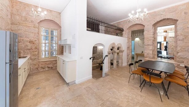 Un'ampia cucina con pareti in pietra, un'area pranzo con tavolo e sedie e una scala che conduce a un piano superiore.