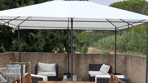 An outdoor patio with a wooden table, chairs, and a large umbrella.