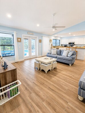 A spacious living area with a sofa, coffee table, and a view of a pool. - Casa Azul - 4Br/2Ba Pool & Spa Home, Sleeps 10 (Port St. Lucie)