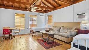 A room with a wooden ceiling, a bed, a sofa, a dining table with chairs, and a small table with a lamp. - Cozy 1BR Near Downtown Lafayette (Lafayette)