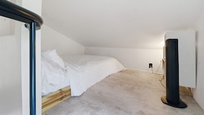 A small, unadorned room with a single bed, a standing heater, and a power outlet on the wall. - Cozy 1BR Near Downtown Lafayette (Lafayette)